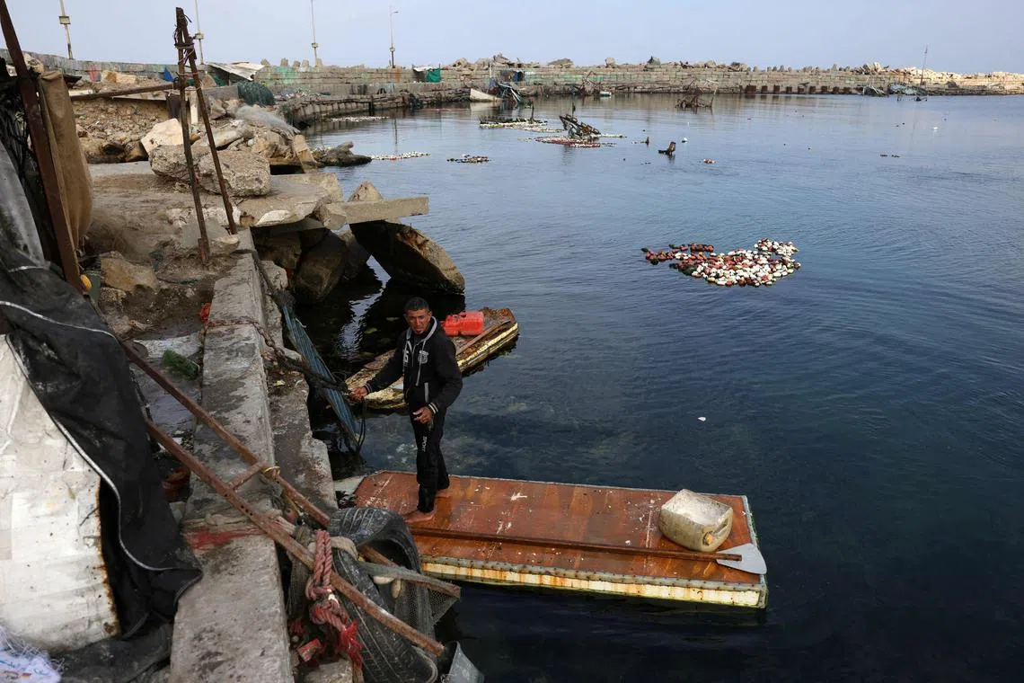 A Palestinian man stands on the door of a refrigerator that he uses as a makeshift rowing boat to catch fish, at the port of Gaza City on March 9.
