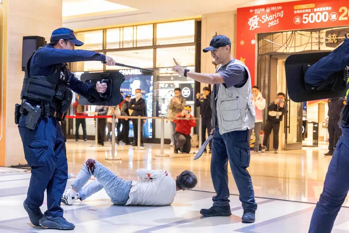Police officers confront a man with a fake knife during a drill following a deadly stabbing rampage in Taipei.

