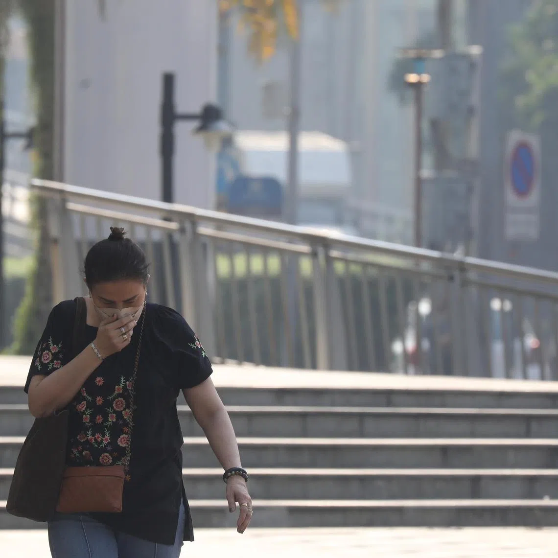 A pedestrian wears a face mask as air pollution of fine particulate matter (PM2.5) at harmful levels shrouds the surroundings in Bangkok, Thailand.