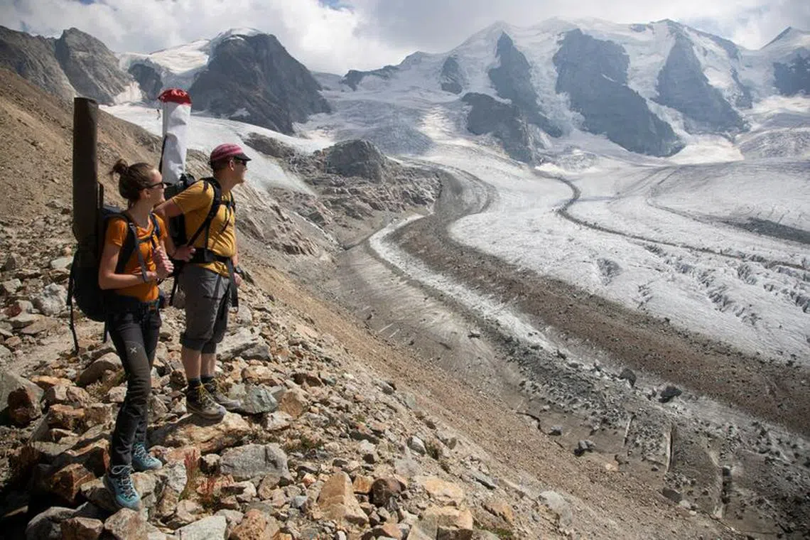 FILE PHOTO: Glaciologist Andreas Linsbauer and assistant Andrea Millhaeusler stand on a border moraine of the Pers Glacier near the Alpine resort of Pontresina, Switzerland July 21, 2022.  REUTERS/Arnd Wiegmann/File Photo