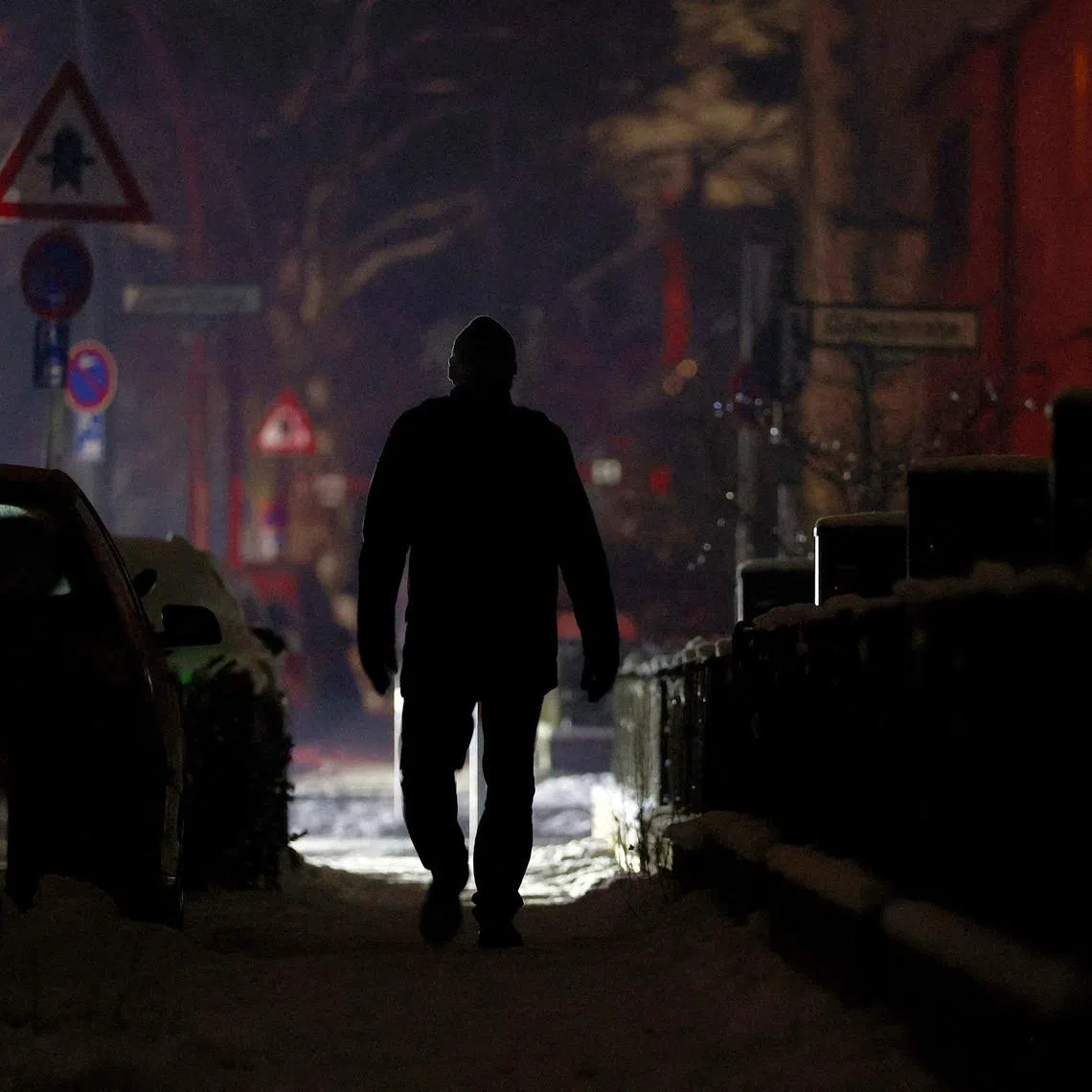 FILE PHOTO: A person walks along a street during a blackout, which left thousands of homes without power after a suspected arson attack at the Lichterfelde power plant in the Steglitz-Zehlendorf district in southern Berlin, Germany, January 6, 2026. REUTERS/Lisi Niesner/File Photo