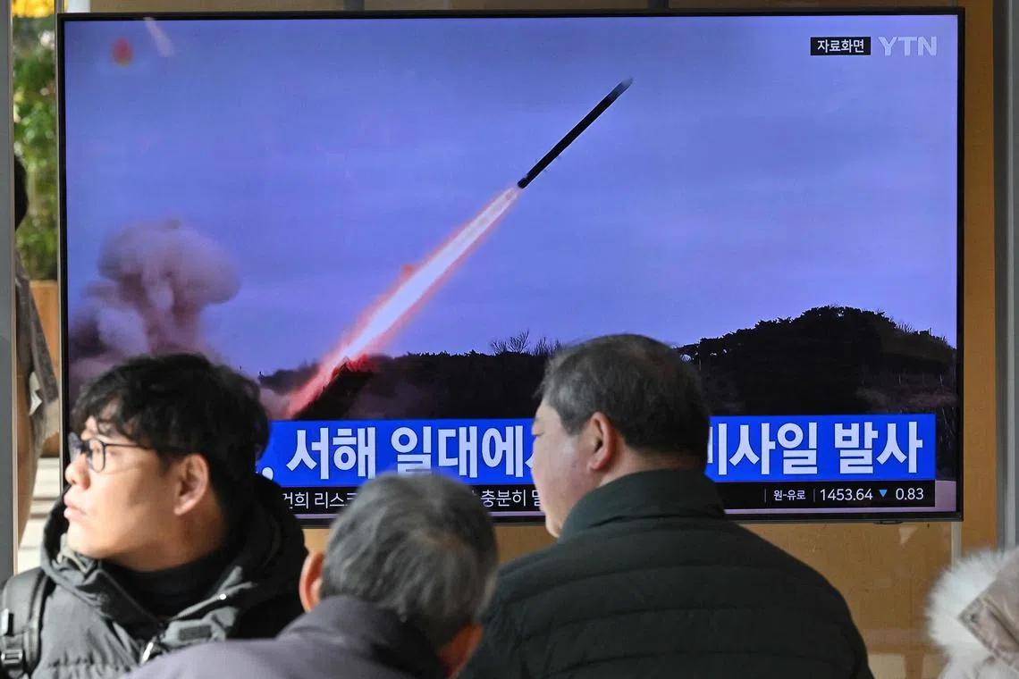 People watch a television screen showing a news broadcast with file footage of a North Korean missile test, at a railway station in Seoul on Jan 24, 2024. 