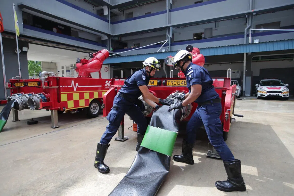 SCDF officers Ismarian Shahidy Mohamed Ishak (left) and Muhammad Syafiq Abdul Gaffur attaching 12-inch hoses to the 40,000 LPM Monitor during a demonstration in February.