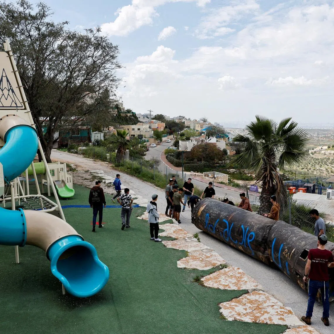 FILE PHOTO: Teenagers drag a part of a missile that landed in the playground of an elementary school last night, amid the U.S.-Israel conflict with Iran, in the Israeli settlement Peduel of the Israel-occupied West Bank, March 23, 2026. REUTERS/Amir Cohen/File Photo