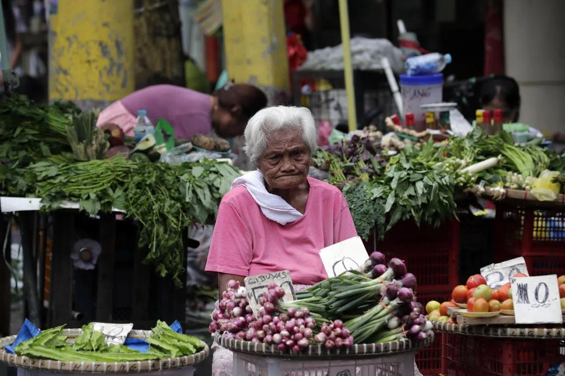 An eldery woman sells spring onions and other vegetables at a market in Manila, Philippines, on January 17, 2023.