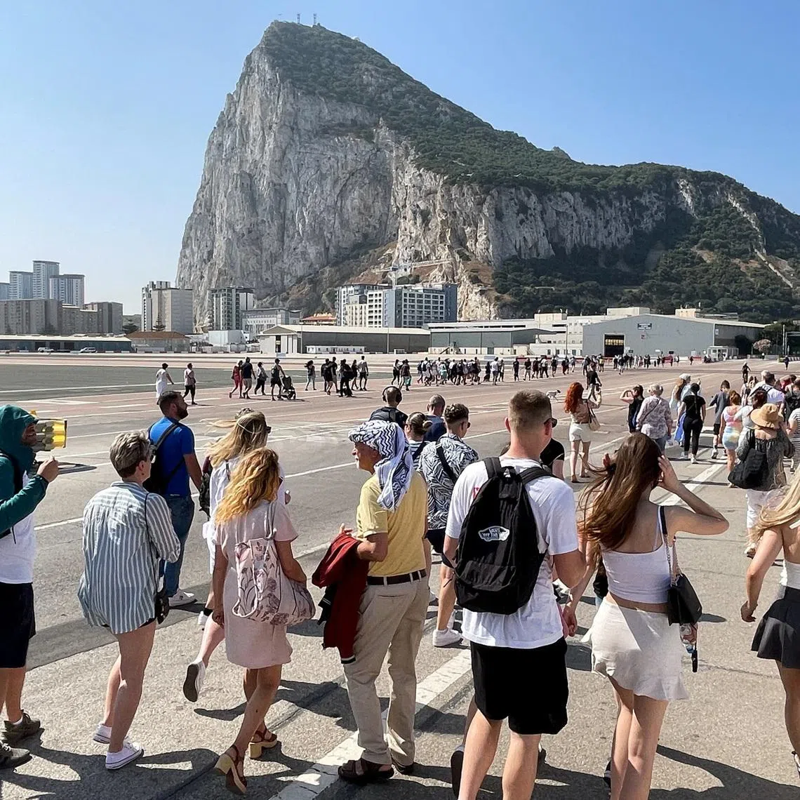 FILE PHOTO: Tourists cross the tarmac of the airport in front of the Rock, as they walk towards the city centre after crossing the border from Spain, after the European Union (EU) and Britain reached an agreement on the status of the overseas territory of Gibraltar, in Gibraltar, Spain, June 12, 2025. REUTERS/Jon Nazca/File Photo