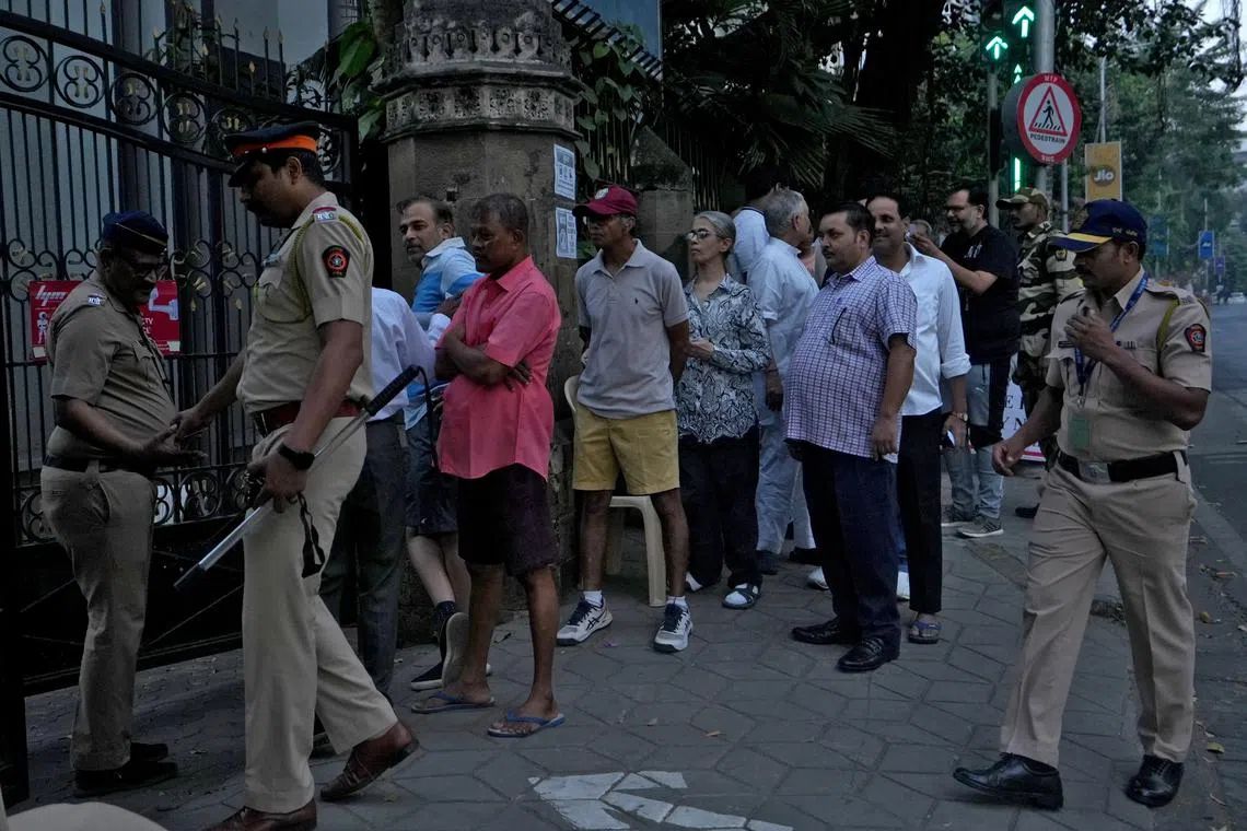 People queue to cast their votes, outside a polling station, as police officers stand guard on the day of the Maharashtra state elections, in Mumbai, India, November 20, 2024. REUTERS/Hemanshi Kamani