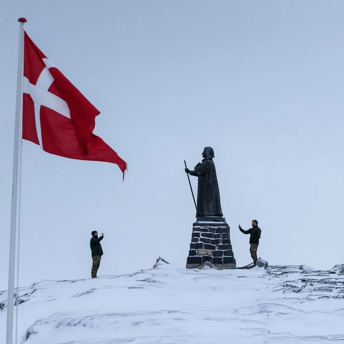 Danish soldiers take pictures next to the statue of Hans Egede, at Nuuk's old harbour, Greenland, January 18, 2026. REUTERS/Marko Djurica