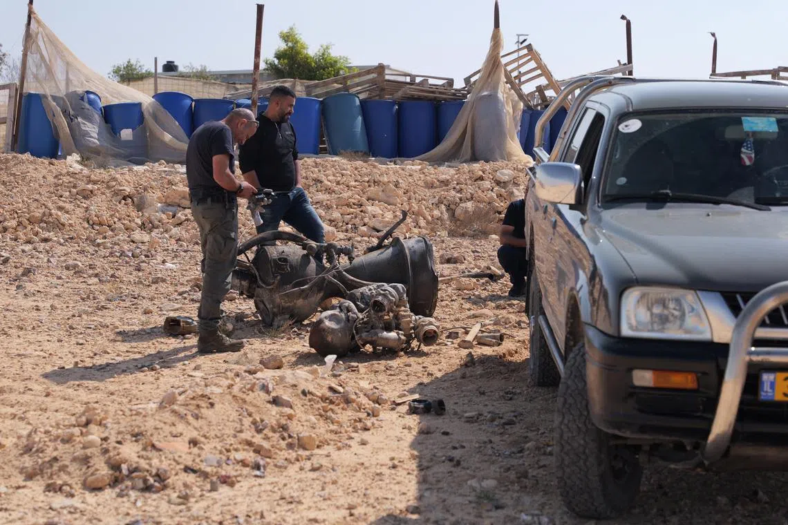 A police officer inspects the remains of a rocket booster that, according to Israeli authorities, critically injured a seven-year-old girl, during Iran's weekend attack on Israel.