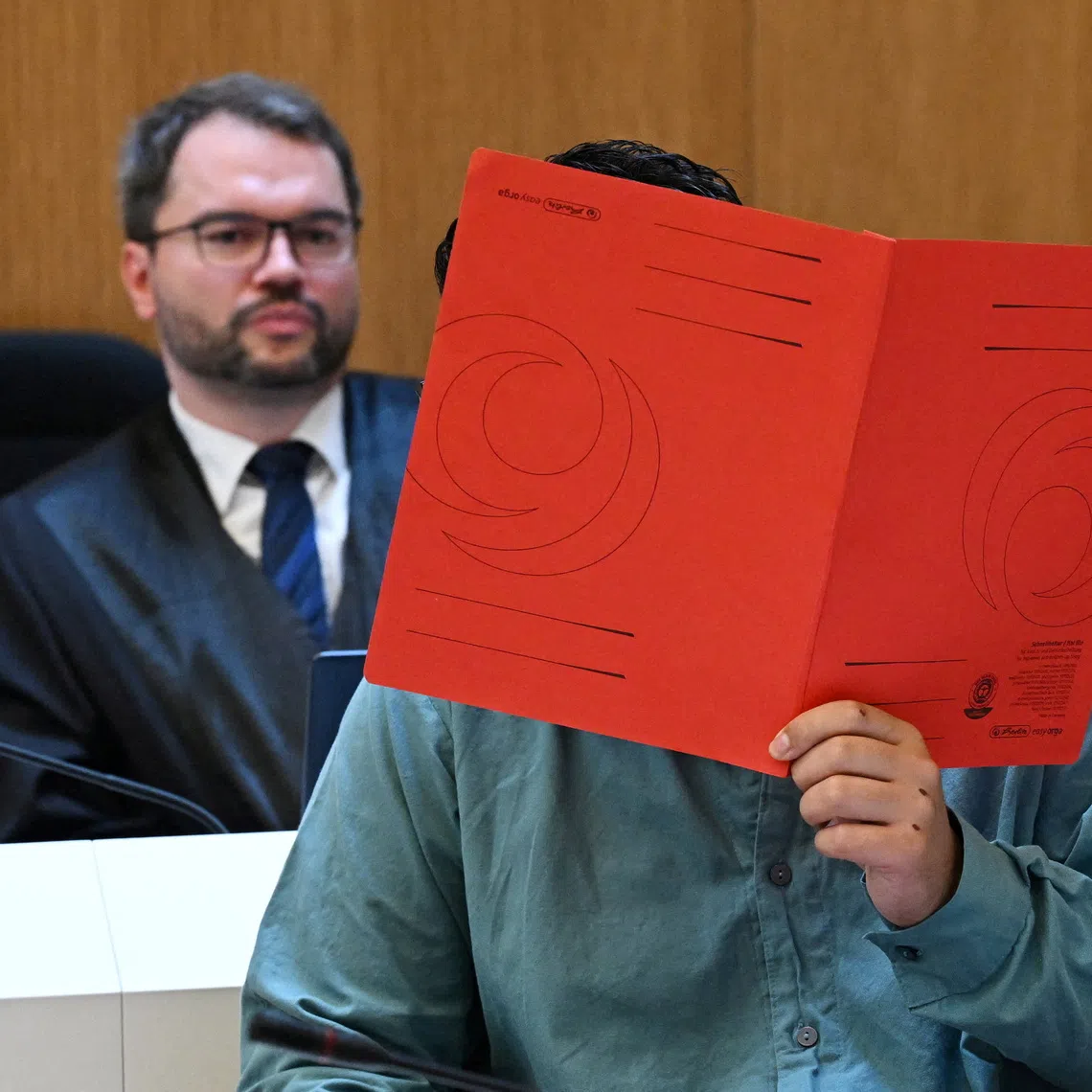 Lawyer Johann Bund and defendant Farhad N., accused of murder and other charges, arrive for his verdict in a courtroom in Munich, Germany, August 6, 2026. REUTERS/Angelika Warmuth