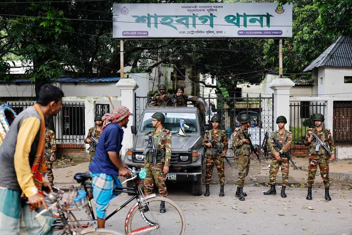 Rickshaw drivers pass army personnel standing guard in front of a police station to protect police from being attacked.