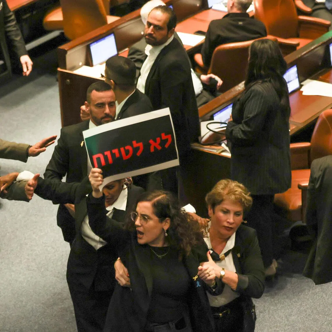 Knesset member Naama Lazimi holds a banner reading "do not cover up", as she is escorted out by Knesset ushers during a debate on the Oct 7 investigation Bill on Dec 24.