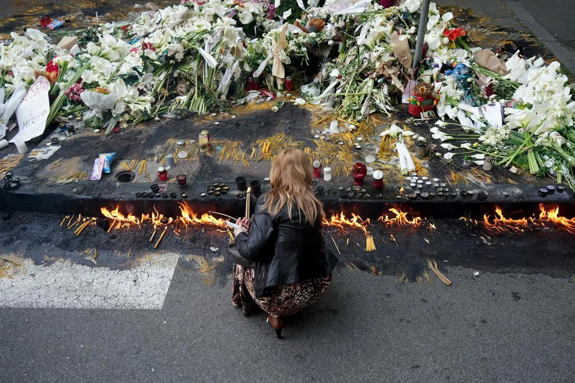 A woman lights candles outside the Vladislav Ribnikar elementary school in the capital Belgrade.