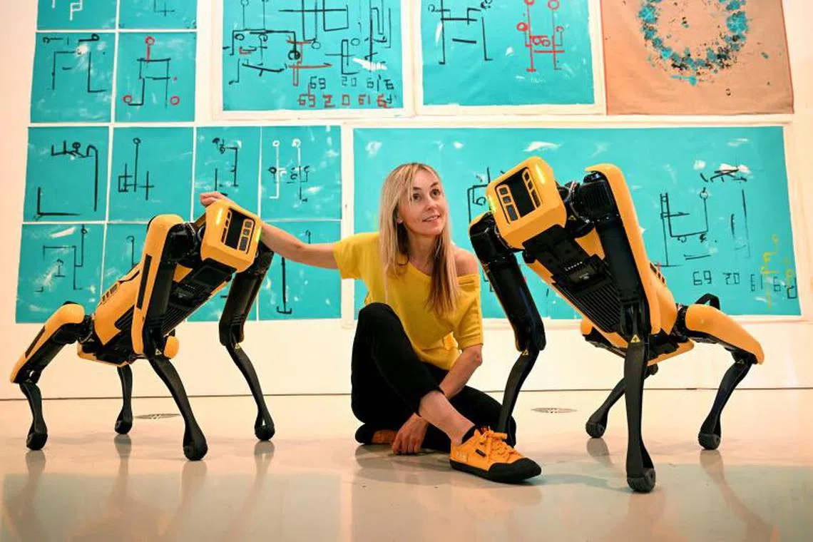 Polish artist Agnieszka Pilat poses with the artwork of her robot painting dogs Basia Spot and Bunny Spot who have become artists painting on canvases with their paws, at the launch of the National Gallery of Victoria (NGV) Triennial 2023 in Melbourne on April 5, 2023. 