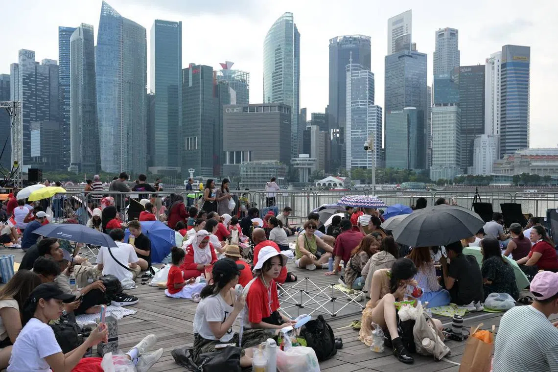 People were out in force with umbrellas and picnic mats as they gathered ahead of the National Day Parade on Aug 9.