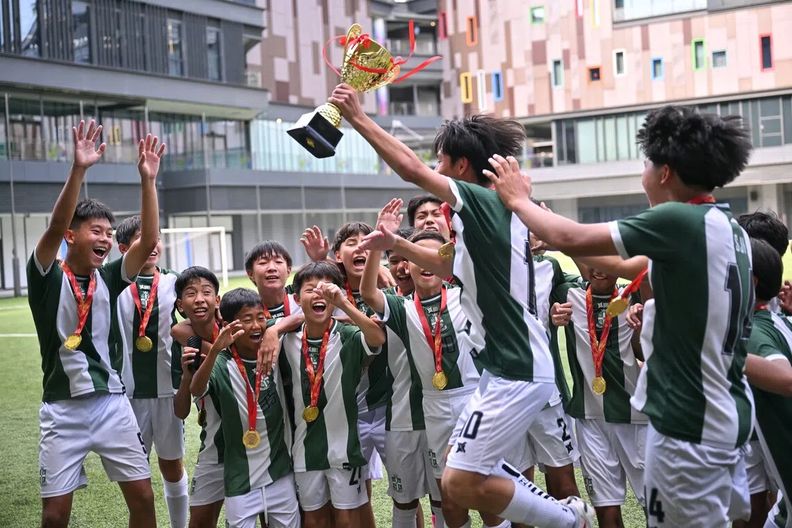 St Joseph’s Institution captain Zayden Ng lifting the trophy during his team’s celebration after they beat St Gabriel’s Secondary School 3-0 to win the C Division boys’ football final for a third straight year.