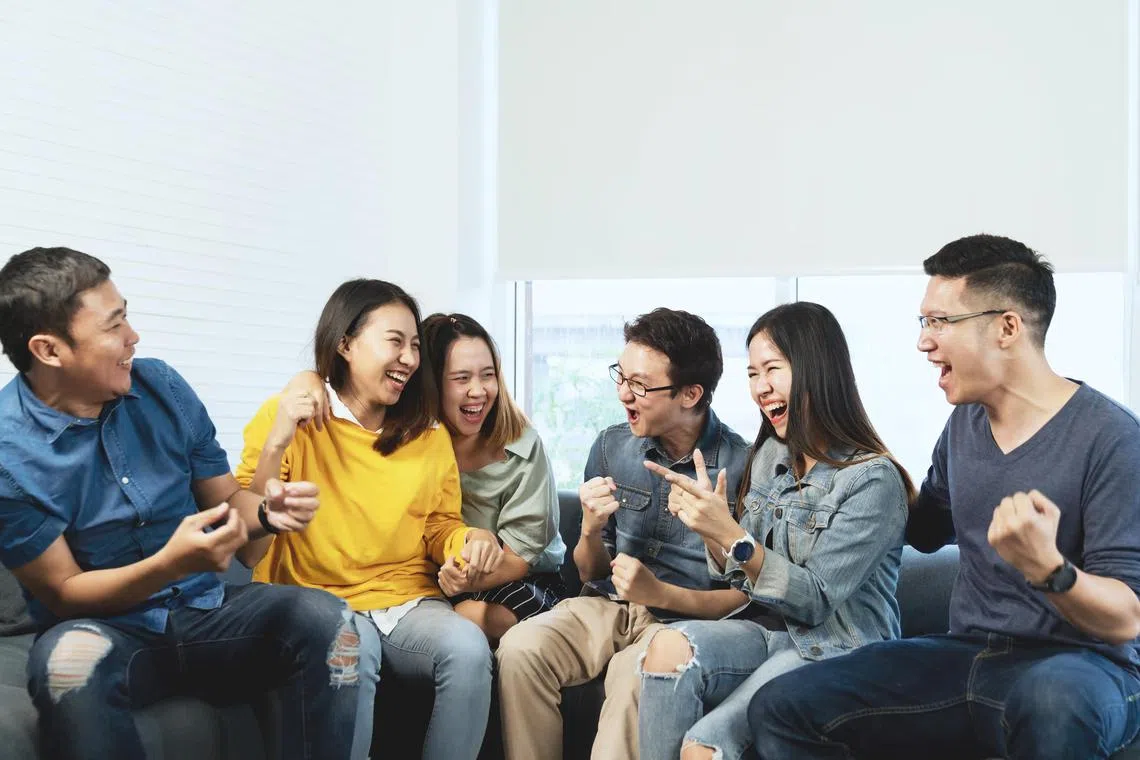 Young Attractive asian group of friends talking and laughing with happy in gathering meeting sitting at home feeling cheerful and enjoy game in leisure time together. People in blue or yellow wearing.