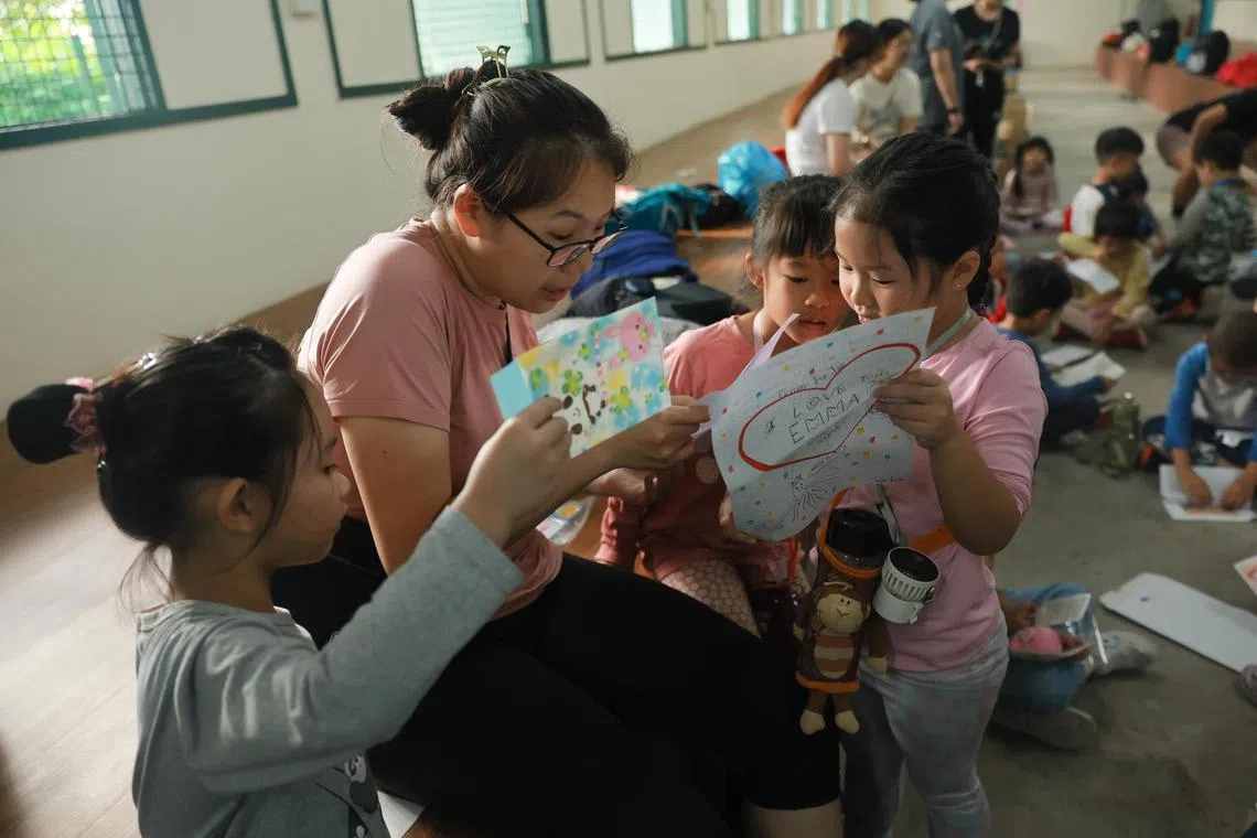 (For print) 
Teacher Samantha Teo 33 surrounded by (L-R) Li Yuncheng, Joanna Wong and Emma Soh to get help in reading aloud the handwritten letters from their families - a long-held tradition. 