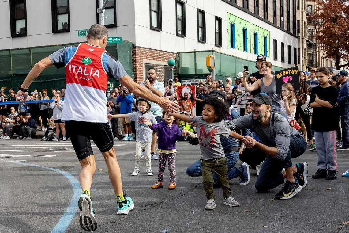 A runner high fives spectators during the TCS New York City Marathon in the United States,  Nov 6, 2022.