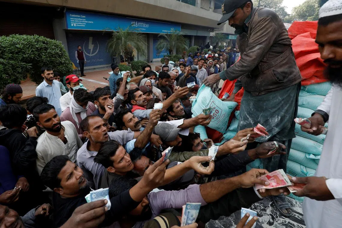 Men reach out to buy subsidised flour sacks from a truck in Karachi, Pakistan, on Jan 10, 2023.