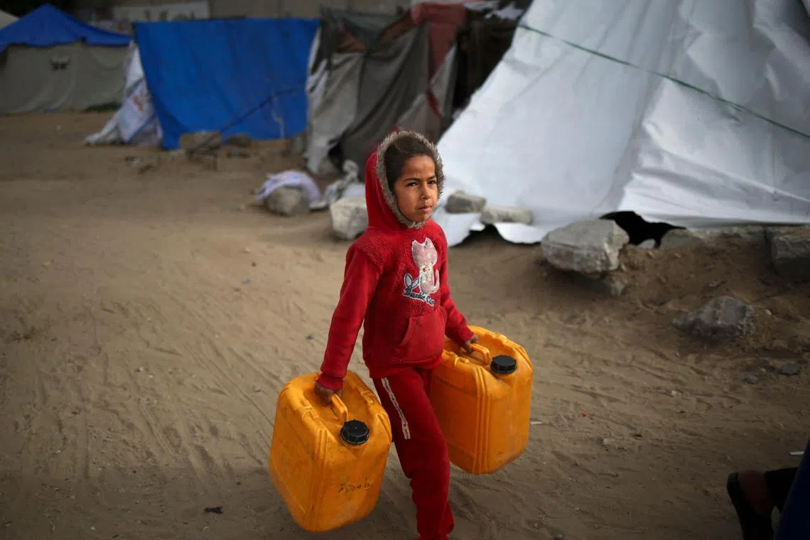 A Palestinian girl carries water containers along a street in Rafah in the southern Gaza Strip on March 3, 2024, amid the ongoing conflict between Israel and the Hamas movement. (Photo by AFP)
