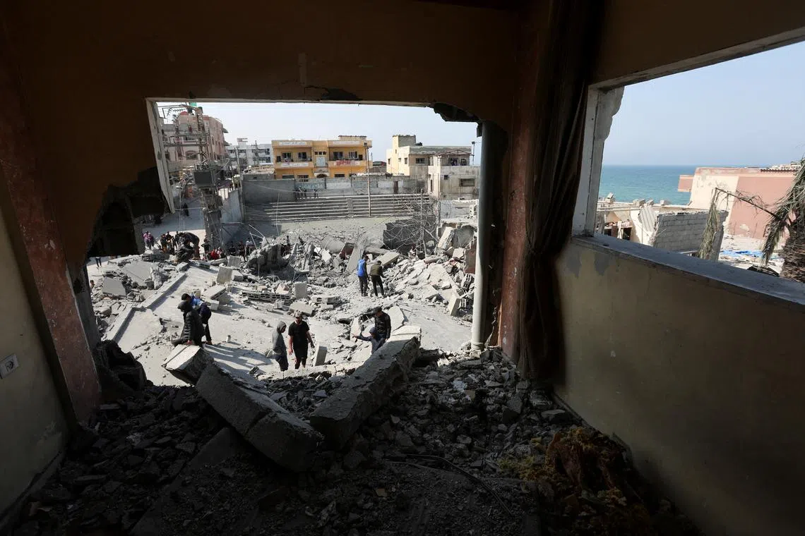 Palestinians inspect the site of an Israeli strike on a residential building, in Deir Al-Balah in the central Gaza Strip March 18, 2025. REUTERS/Ramadan Abed