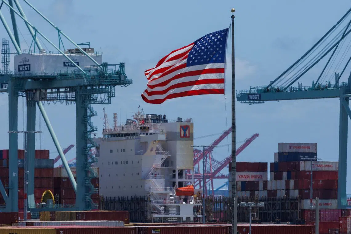 An American flag flutters over a ship and shipping containers at the Port of Los Angeles, in San Pedro California, U.S., May 13, 2025. REUTERS/Mike Blake/File Photo