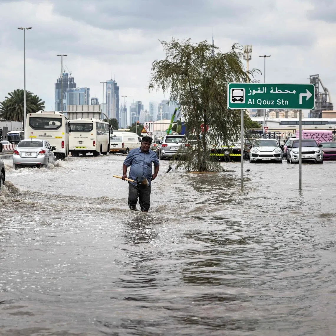 A man carries a spade to unblock a drain as he walks through floodwaters following heavy rains in Dubai.
