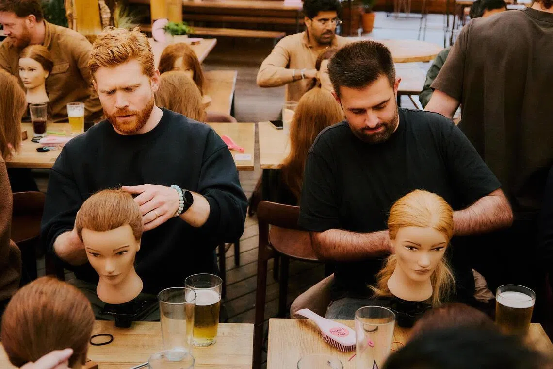 Fathers using mannequins to learn about hairstyling children at a “Pints and Ponytails” happy hour at a rooftop bar in South London on May 19.