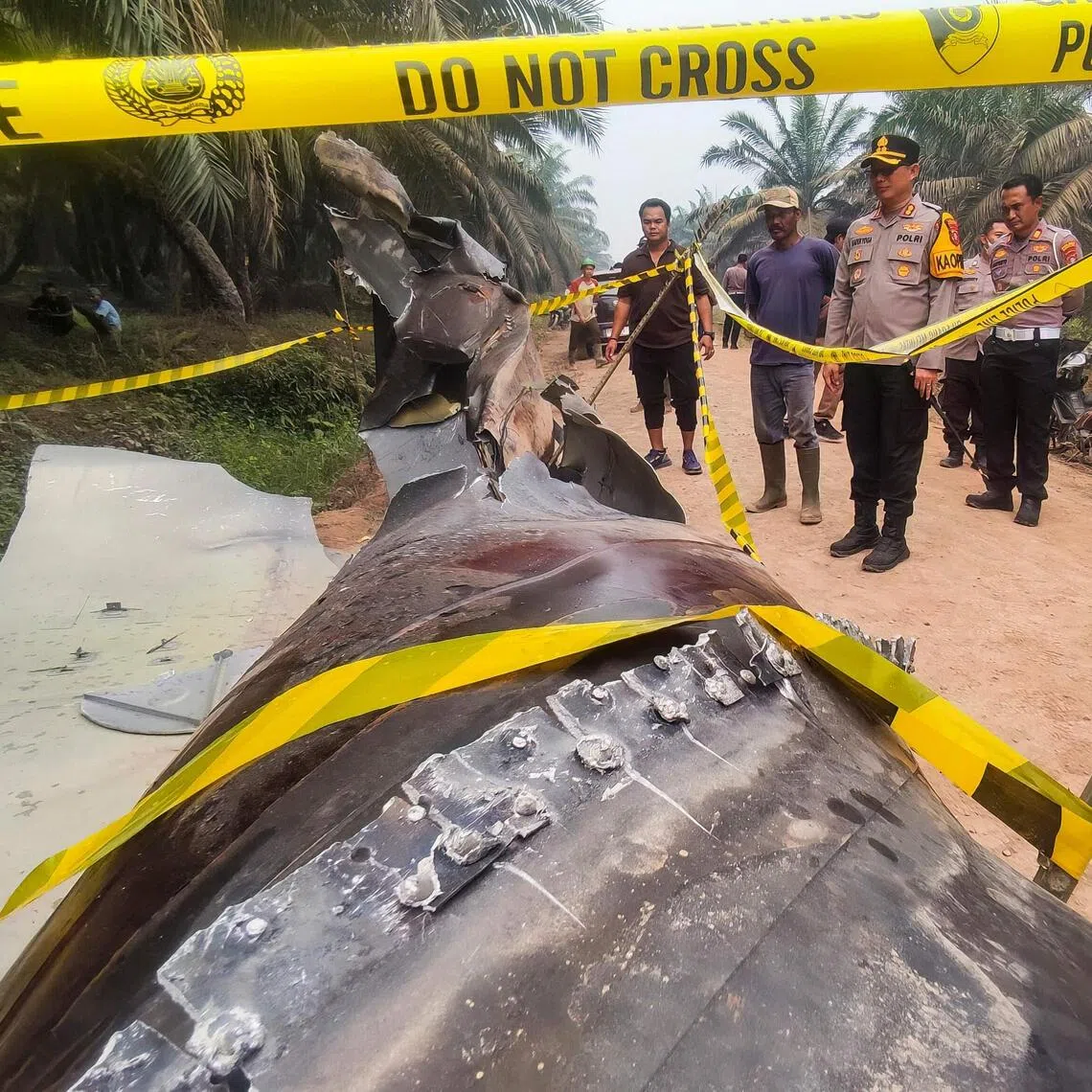 Indonesian police officers inspecting a large charred metallic fragment, suspected to be rocket debris, at an oil palm plantation in East Kotawaringin Regency, in Indonesia’s Central Kalimantan province on Oct 19.