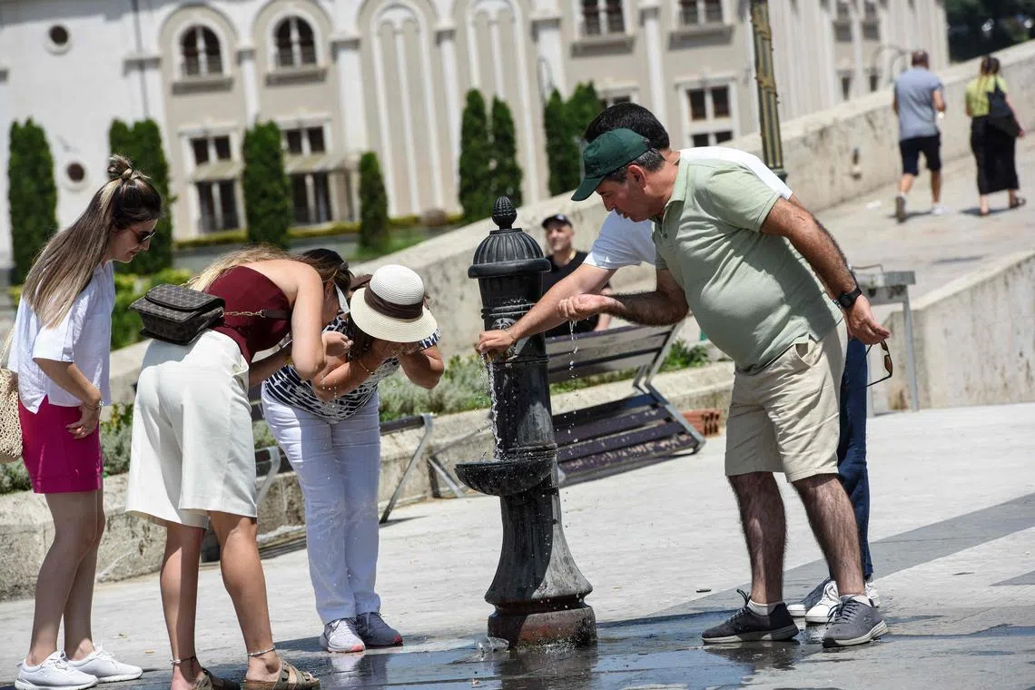 Members of the public try to cool of at a public fountain in Skopje, on July 24,2023, as for over a week North Macedonia is facing orange warning for extreme temperatures going between 38 and 42 degrees. Citizens were advised by the Government to take all needed measures to protect themselves from the extreme heat, recommended pregnant women and people older than 60 to stay home and not to be exposed to sun longer period of time after 11 a.m. (Photo by Robert ATANASOVSKI / AFP)