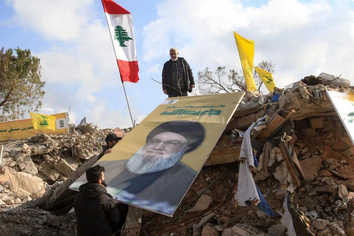 People place a picture of slain Hezbollah leader Hassan Nasrallah over the rubble of the shrine of Shamoun al-Safa, built within a castle in the village of Shamaa in southern Lebanon's Tyre governorate on Jan 31, 2025, that was heavily damaged by Israeli bombing. 