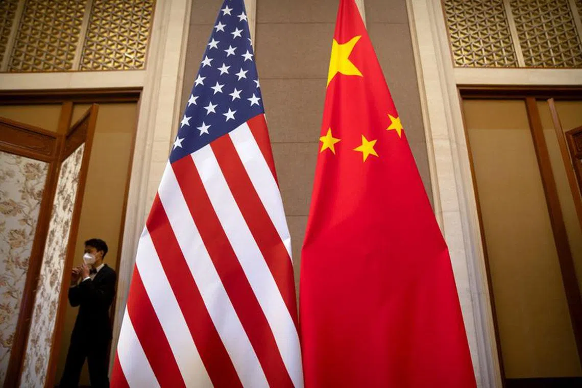 FILE PHOTO: A staff member wearing a face mask walks past United States and Chinese flags set up before a meeting between Treasury Secretary Janet Yellen and Chinese Vice Premier He Lifeng at the Diaoyutai State Guesthouse in Beijing, China, Saturday, July 8, 2023. Mark Schiefelbein/Pool via REUTERS/File Photo