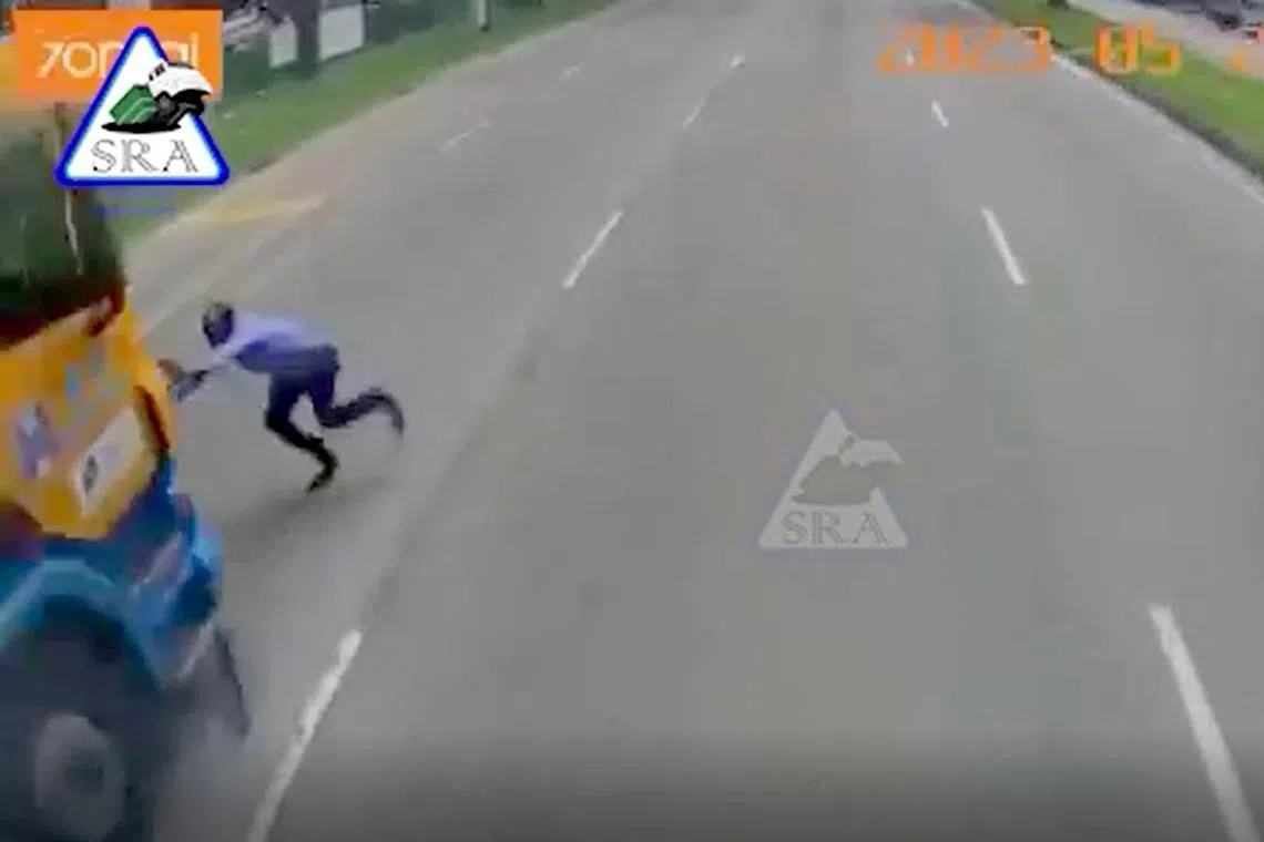 The man makes it across two lanes before an orange-and-blue trailer collides with him and grinds to a halt thereafter.