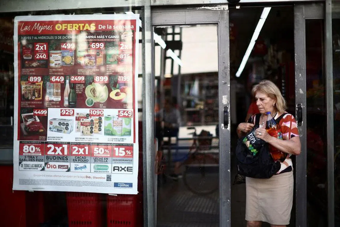 FILE PHOTO: A woman exits a supermarket displaying prices for different products on it's window in Buenos Aires, Argentina, December 12, 2023. REUTERS/Tomas Cuesta/File Photo