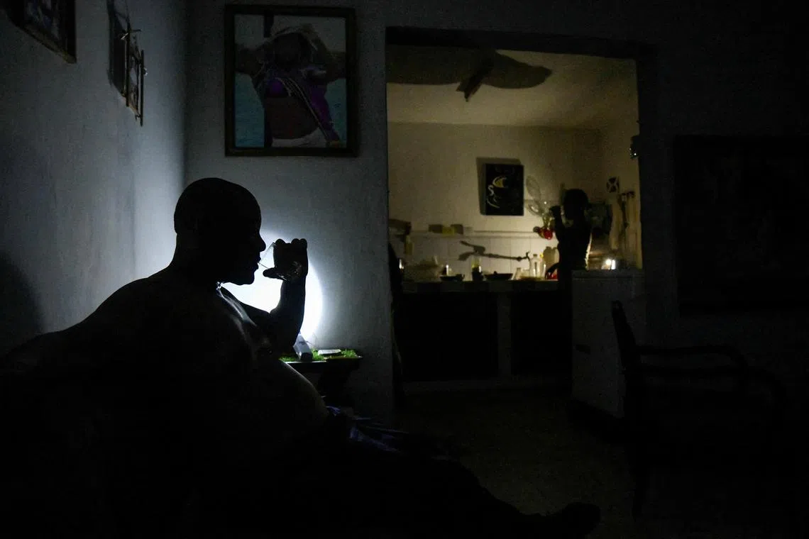 FILE PHOTO: A man drinks water at his home during a power outage caused by breakdowns forcing six plants to go off-line on the grid, according to the state run power company, in Matanzas, Cuba August 22, 2024. REUTERS/Norlys Perez/File Photo