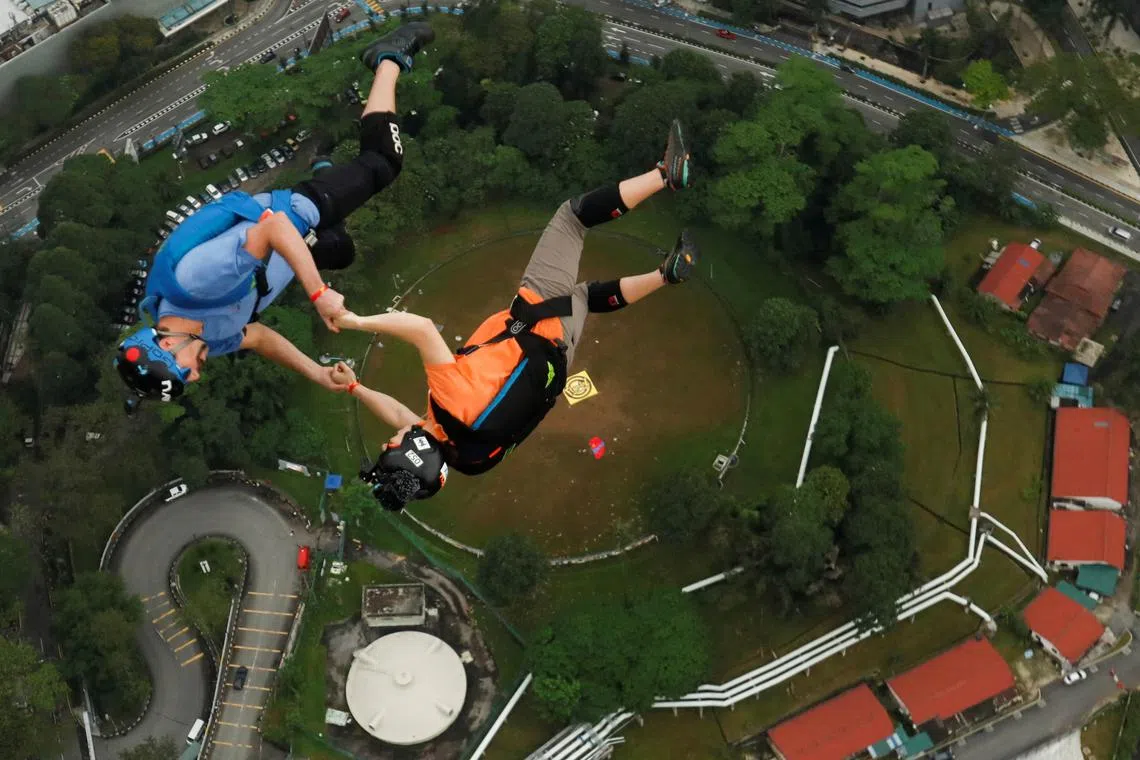 Base jumpers hold hands as they leap off the Kuala Lumpur Tower during the annual KL Tower International Jump Malaysia 2023 at Kuala Lumpur, Malaysia, Feb 3, 2023.