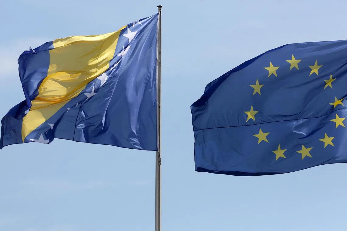 (FILES) In this file photo taken on August 13, 2018, the national flag of Bosnia and Herzegovina (L) is pictured next to the European Union flag during a welcoming ceremony for Bosnia's Chairman of the Council of Ministers, at the Chancellery in Berlin. - EU countries agreed December 13, 2022, to grant Bosnia "candidate status" to join the union, diplomats told AFP, putting the volatile Balkan nation at the start of a long road to membership. European affairs ministers meeting in Brussels gave the green light to the move after the bloc's executive arm in October recommended that they launch the membership process. (Photo by Adam BERRY / AFP)
