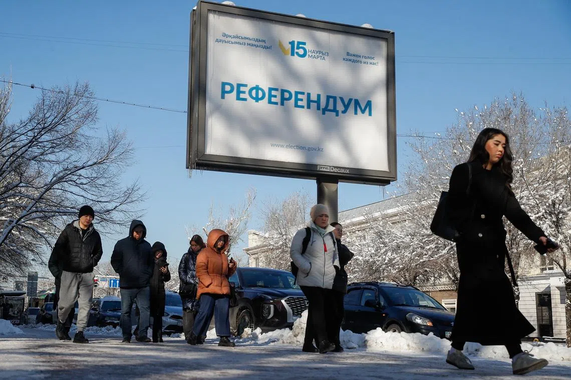 People walk past a campaign poster for a referendum on a new constitution in Almaty, Kazakhstan, March 12, 2026.  REUTERS/Pavel Mikheyev
