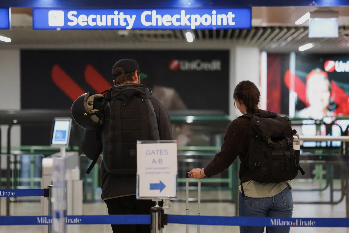 FILE PHOTO: People walk next to a document verification checkpoint at Linate Airport in Milan, Italy, May 2, 2024. REUTERS/Claudia Greco/File Photo