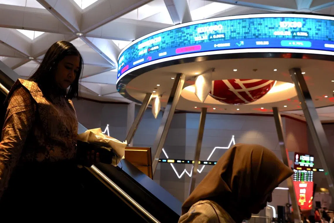People walk as stock prices are displayed on the LCD board at the Indonesian stock exchange building in Jakarta, Indonesia, 13 April 2026. 