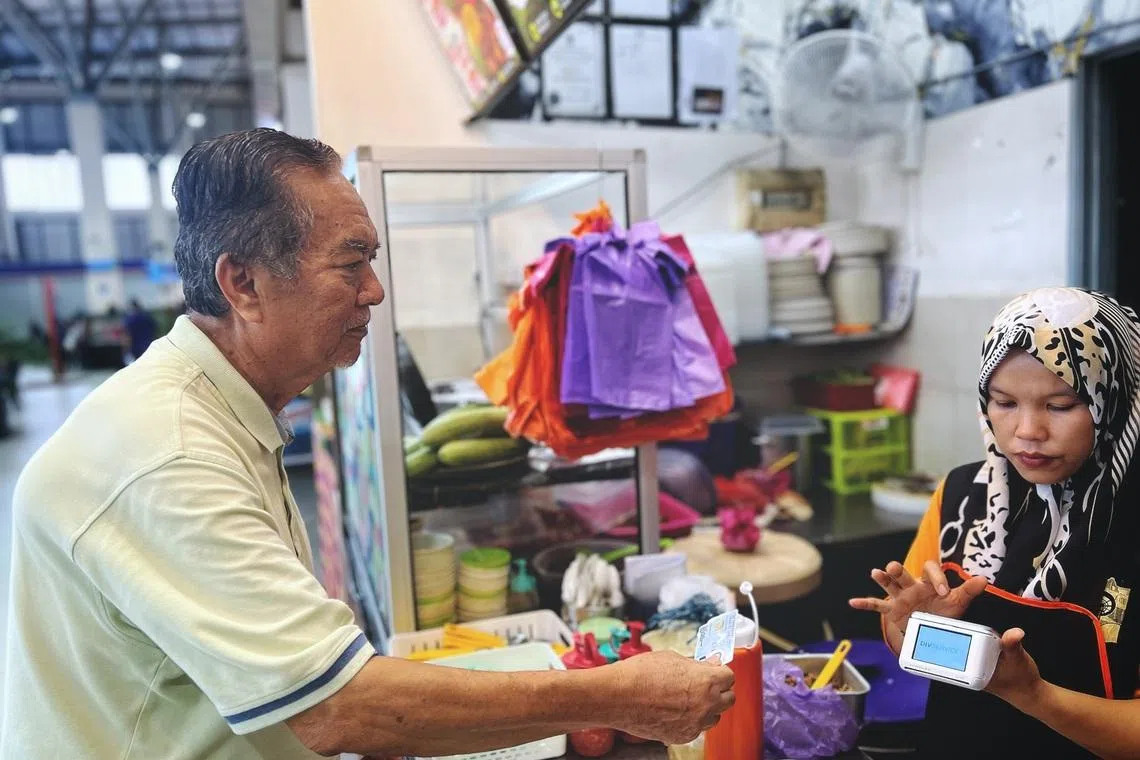 Mr Noran Adan presenting his MyKad to pay for a meal using his Bantuan Kasih Johor cash aid on May 14.