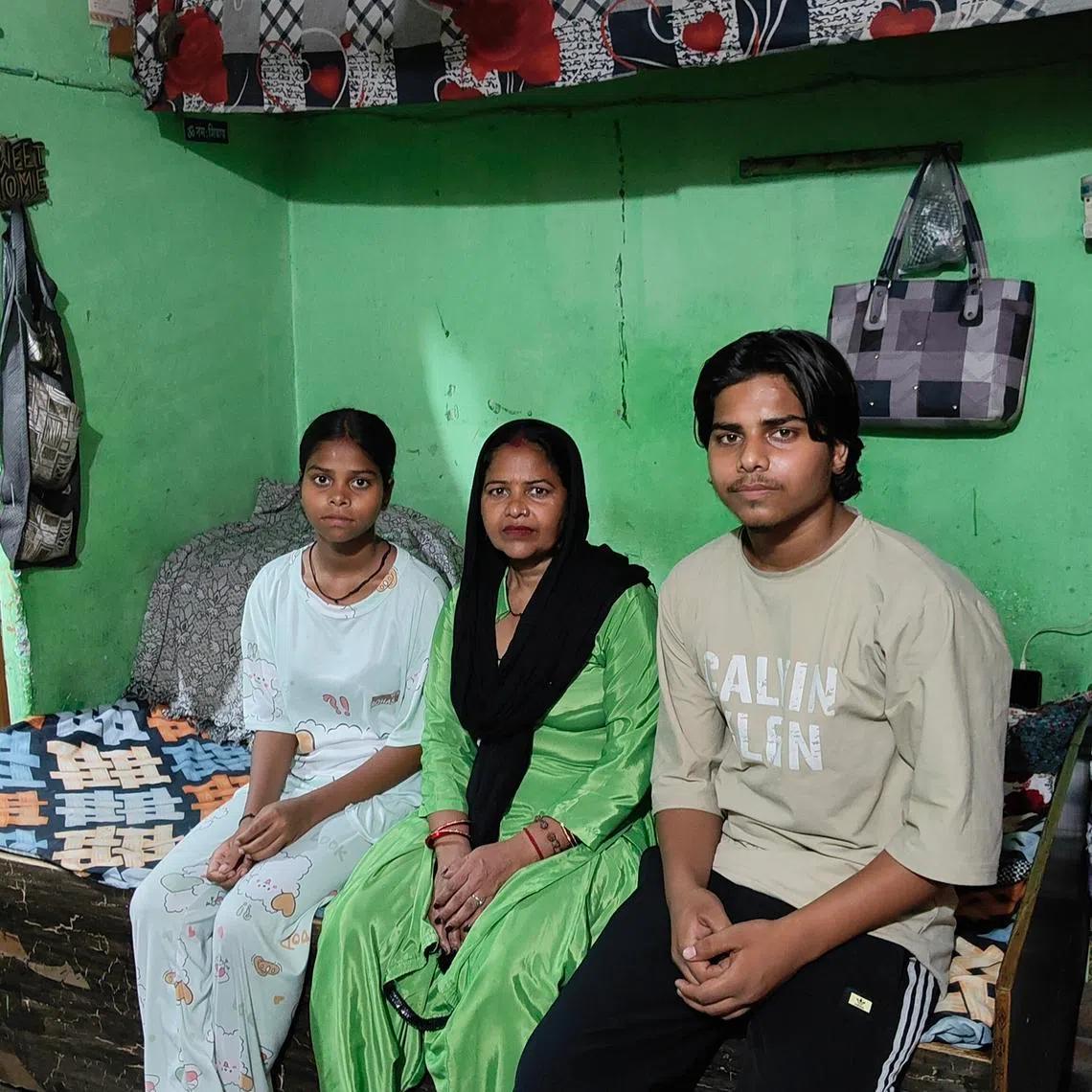 Durga Devi (centre) with her daughter Kinjal (left) and son Abhishek in their window-less one-room rented flat in Delhi. The room feels like a furnace on
