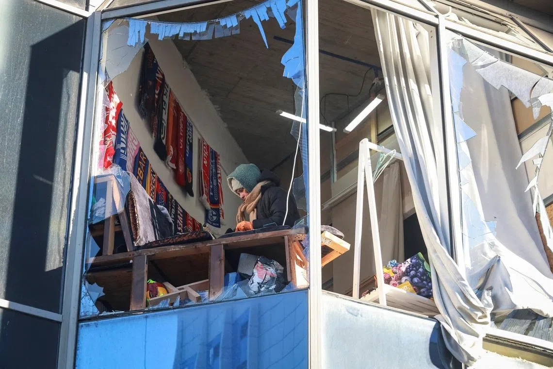A woman appears in a broken window of a building hit by a Russian drone strike, amid Russia's attack on Ukraine, in Odesa, Ukraine, February 9, 2026. REUTERS/Nina Liashonok
