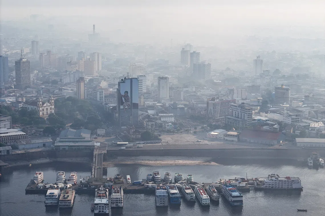 A drone view shows boats in a port as smoke from Amazon wildfires and a burning landfill hangs over Manaus, Brazil, on Oct 8.