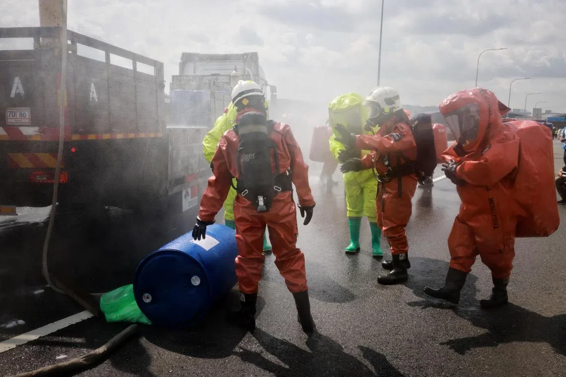 SCDF personnel and their Malaysian counterparts (neon) taking part in an emergency response exercise on tackling a chemical spill incident at the Tuas Second Link, on July 26, 2023. As part of the bilateral cooperation programme under the Malaysia-Singapore Joint Committee on the Environment (MSJCE), the exercise tested the effectiveness of the chemical spill emergency response plan jointly developed by NEA and DOE to coordinate both countries’ emergency responses to transportation accidents involving hazardous chemicals on the Tuas Second Link. 