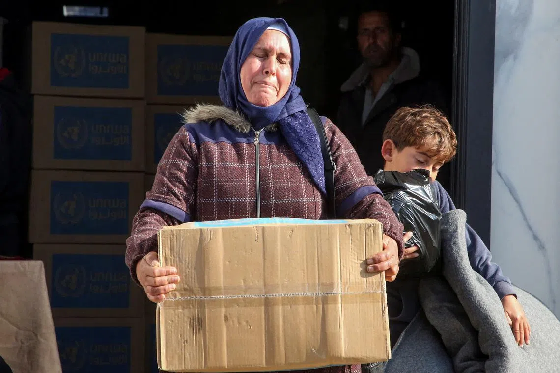 FILE PHOTO: A Palestinian woman carries an aid box she received from an UNRWA distribution point, amid a ceasefire between Israel and Hamas, in Khan Younis in the southern Gaza Strip, February 4, 2025. REUTERS/Hatem Khaled/File Photo