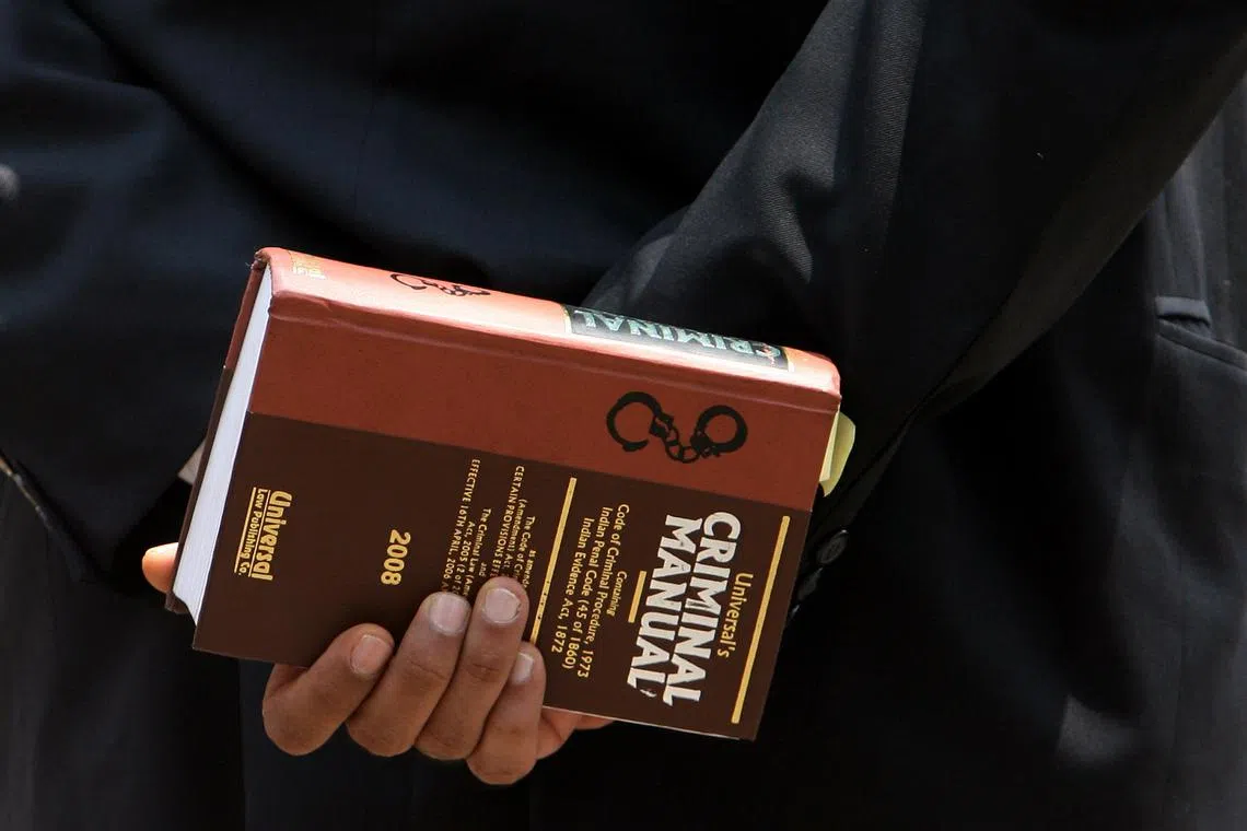FILE PHOTO: A lawyer holds a book as he waits to enter the Arthur Road jail in Mumbai April 16, 2009. REUTERS/Arko Datta/File Photo