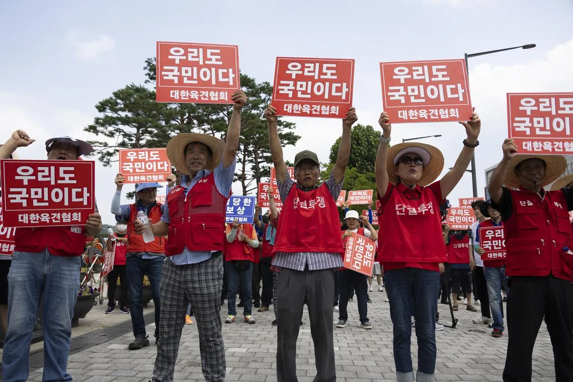 Members of the Korean Dog Meat Association hold banners during a rally against the South Korean government's dog meat policy, outside the presidential office on Aug 1.