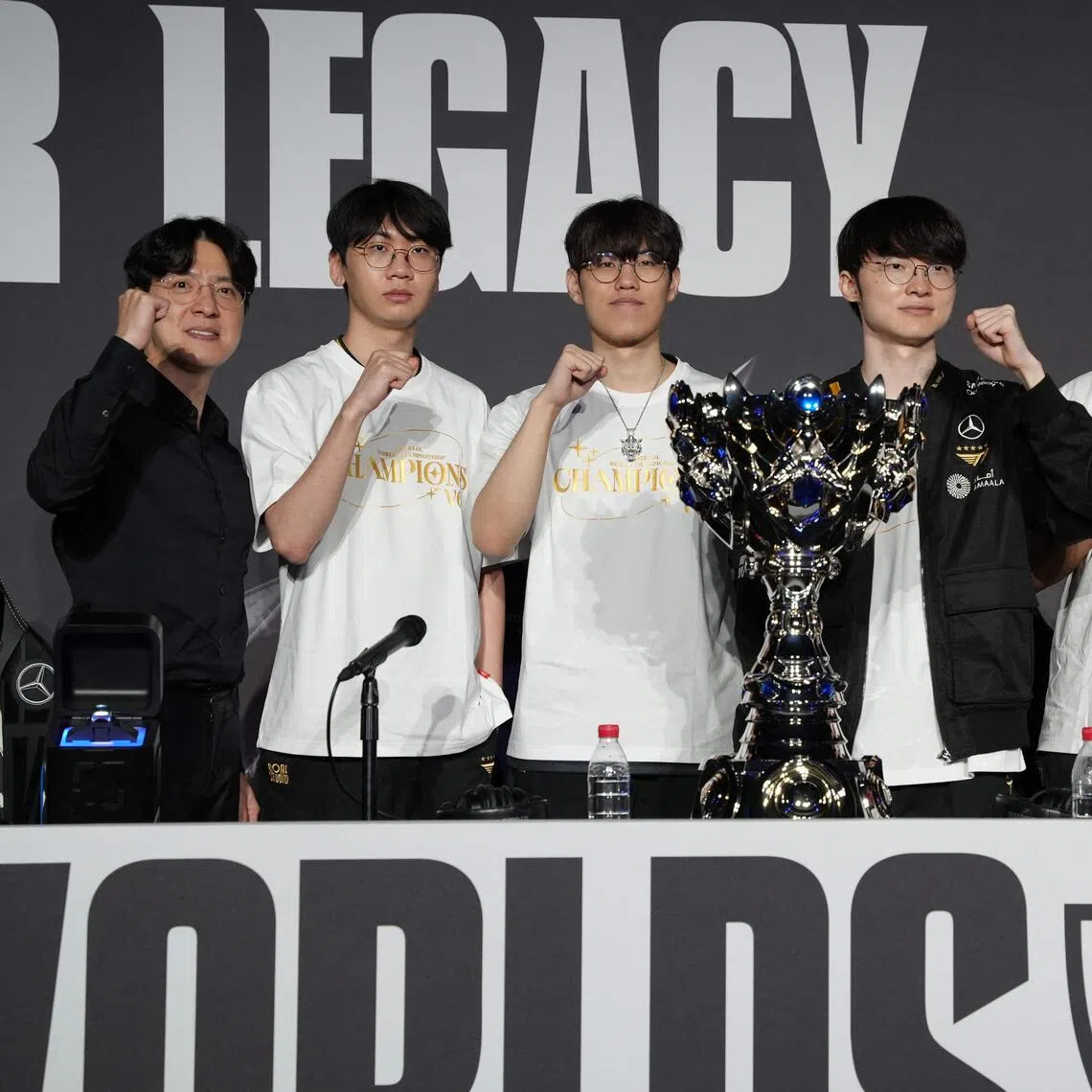 Winners from South Korea's T1 team (from left): coach Kim Jeong-gyun, Doran or Choi Hyeon-joon, Oner or Mun Hyeon-jun, Faker or Lee Sang-hyeok, Gumayusi or Lee Min-hyeong and Keria or Ryu Min-seok pose with the trophy as they celebrate their victory against KT Rolsters.